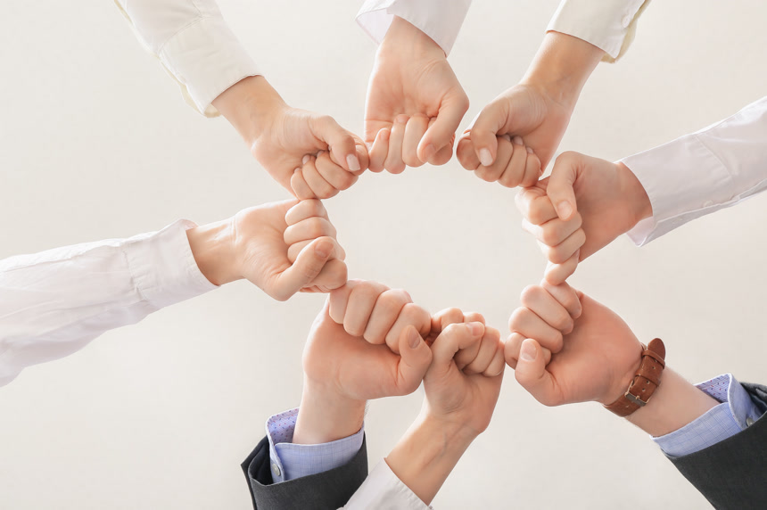 一群商界人士在白种人的背景下聚集在一起握拳连成环团结鼓励