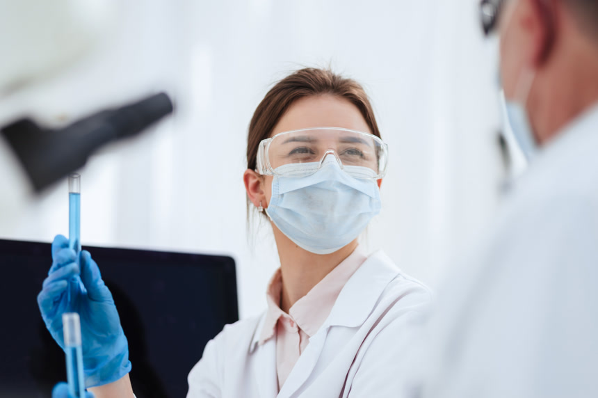 女科学家手中拿着试管中的液体与人交谈医疗健康