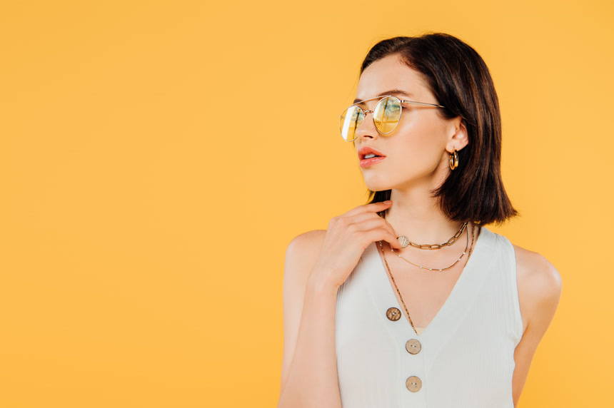 孤立的黄色背景上优雅的女人戴太阳镜上摆出造型生活方式人物模特