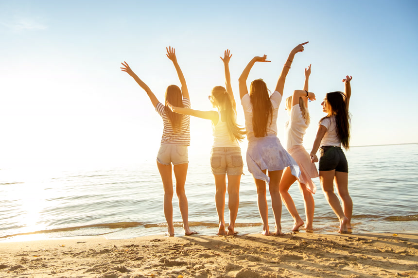 一群女孩面对落日大海高举双手的背影  人像摄影