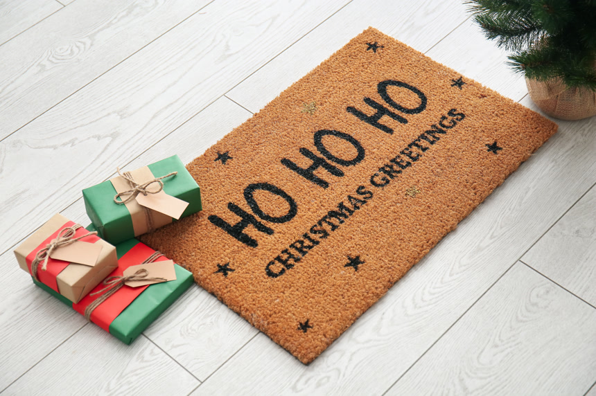 门垫上有圣诞祝福和白色木制地板上的礼物生活方式