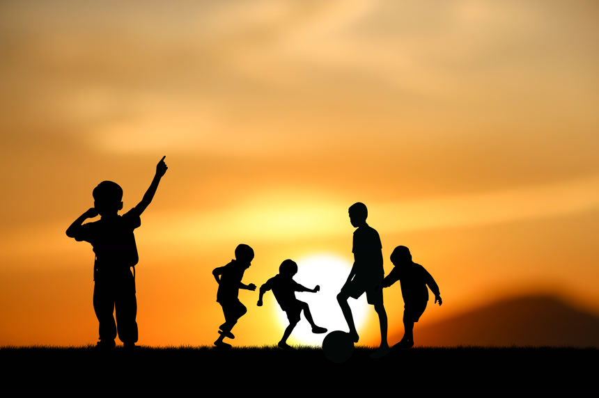 夕阳下踢球的小男孩们的剪影体育运动