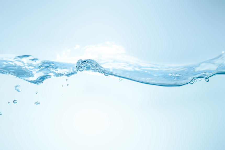 水花洒在蓝色的背景上.水在波浪中流动，并产生气泡。水面上的水滴感觉新鲜而干净.