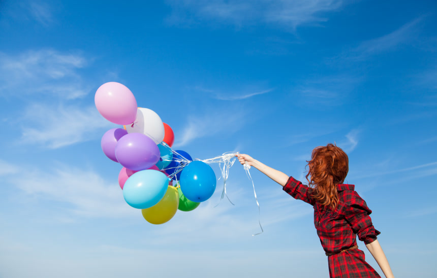 蓝天下牵着五彩气球的女孩图