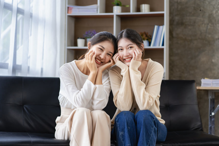 两个亚洲女人坐在沙发上一起玩耍时快乐地摆姿势肖像生活方式