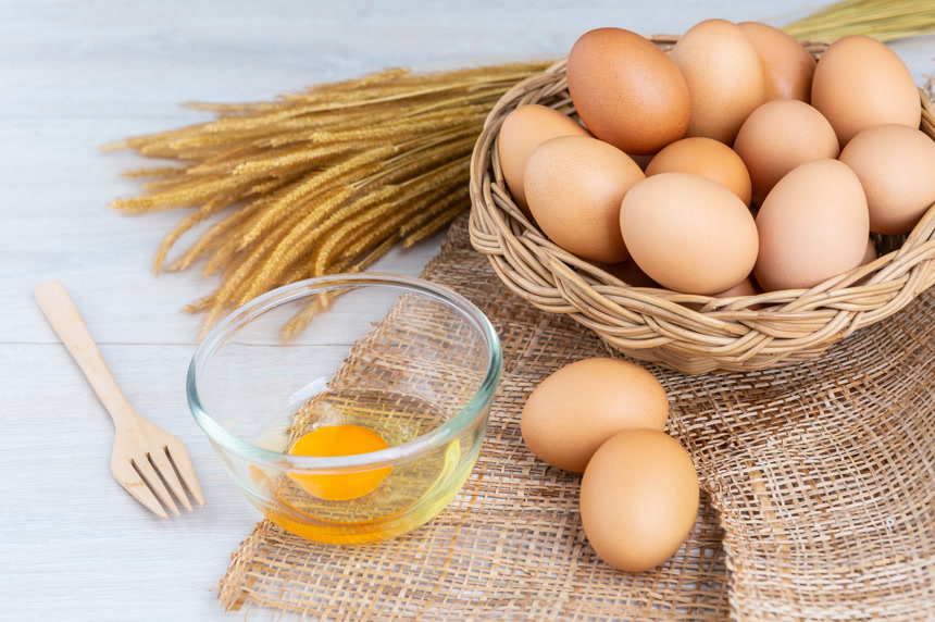 白色桌面上一篮子鸡蛋和玻璃碗里的鸡蛋液特写   超市宣传图