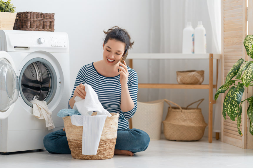 漂亮的年轻女人在家里洗衣服的时候笑了居家生活方式