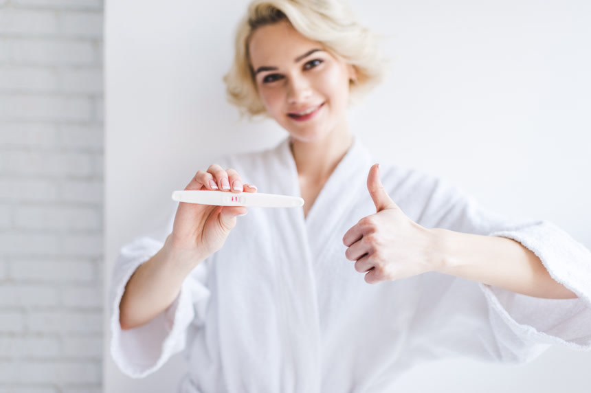 微笑的少妇高兴的举着验孕棒测试纸医疗健康