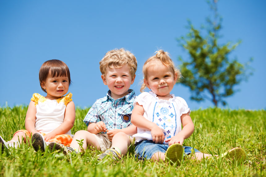 三个坐在草地上的外国小孩微笑高兴写真照片