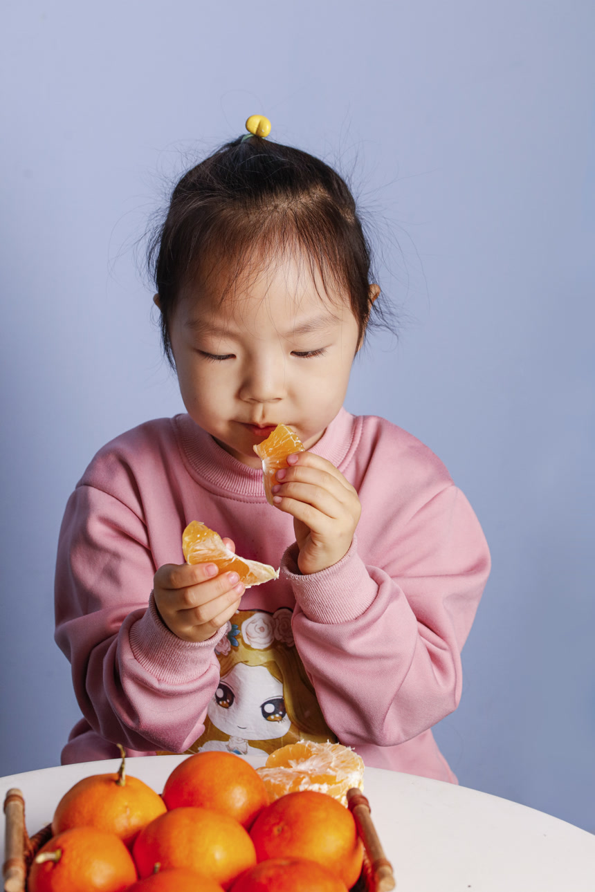 小孩正在吃着蜜桔