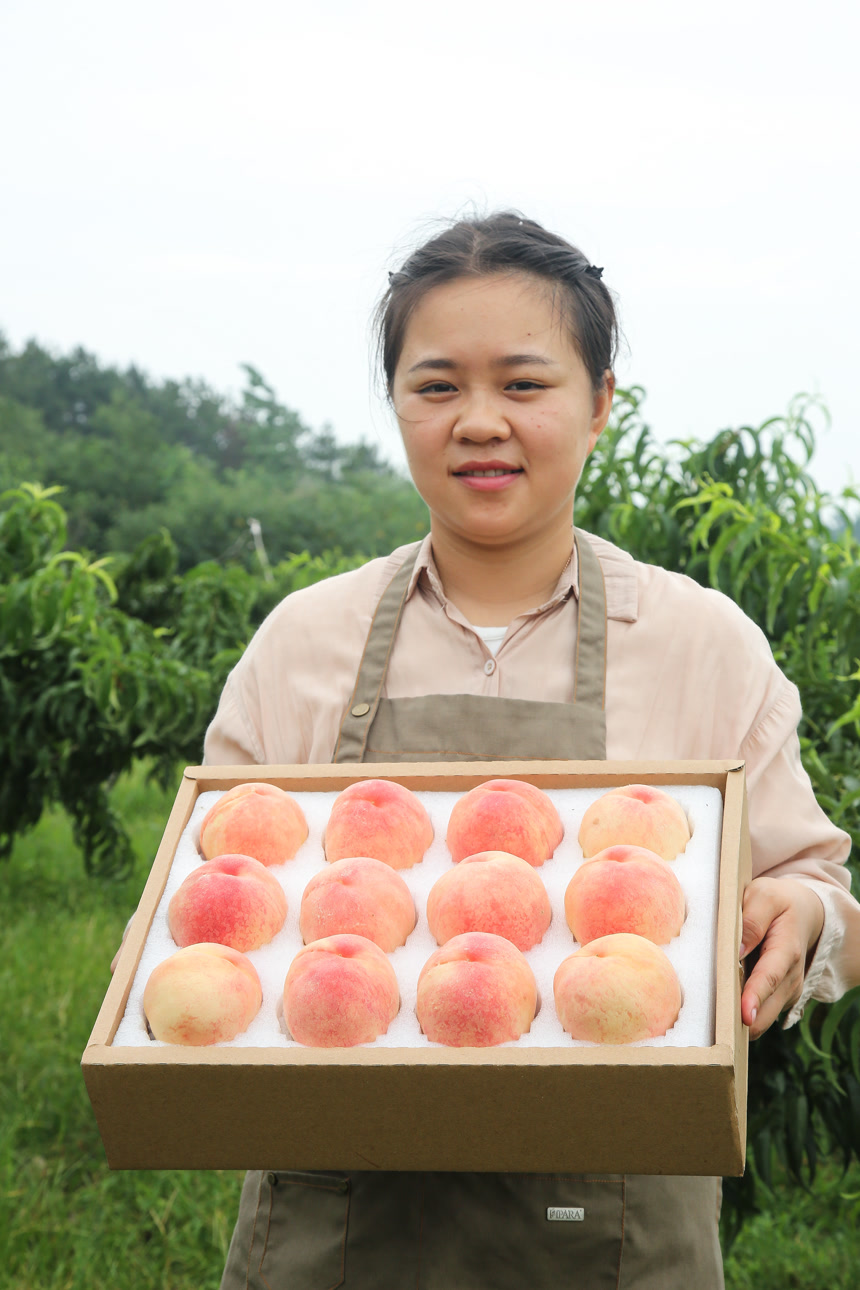 手里拿着一箱阳山水蜜桃