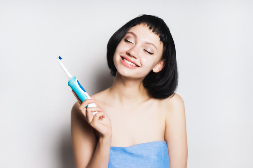 拿着一把电动牙刷的漂亮女孩写真白底图