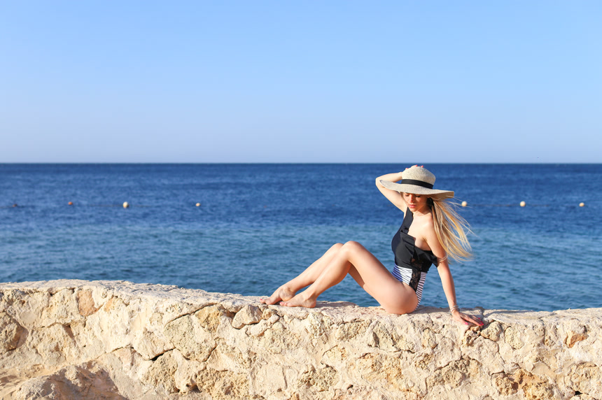 年轻漂亮的性感女人放松在泳衣上与蓝色海洋和天空的背景生活方式