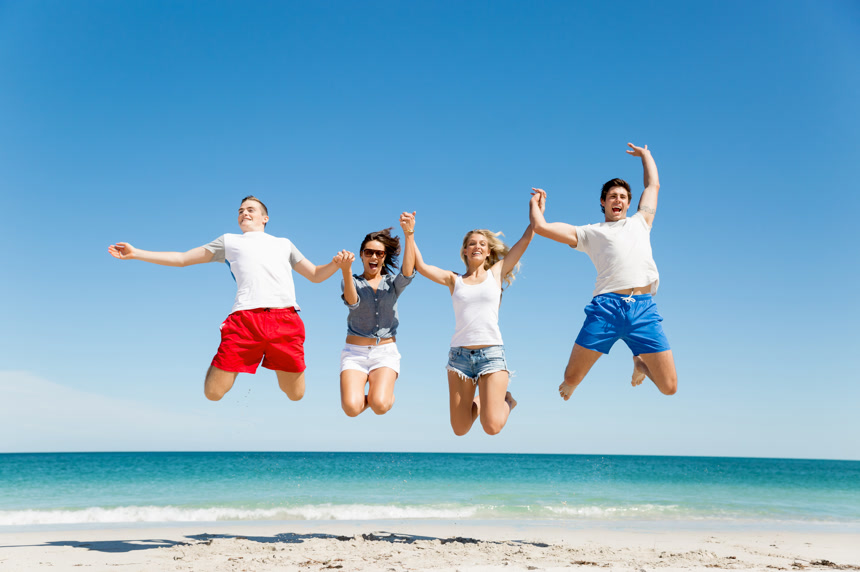 公司的年轻人在海滩上跳跃的照片