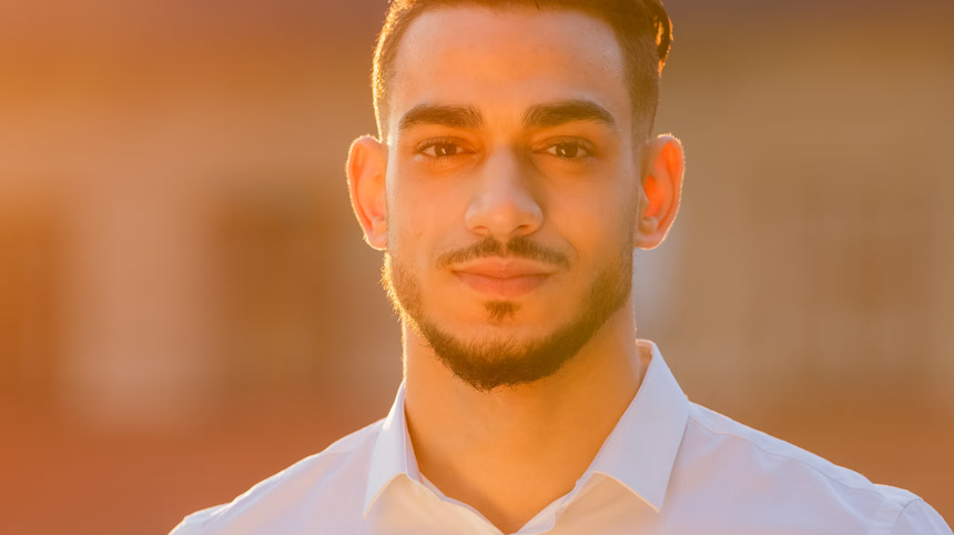 外型阿拉伯裔拉美裔商人老板领导的一位商人穿着白衬衫，站在外边，看着夕阳西下的阳光。特写友好的男性面孔