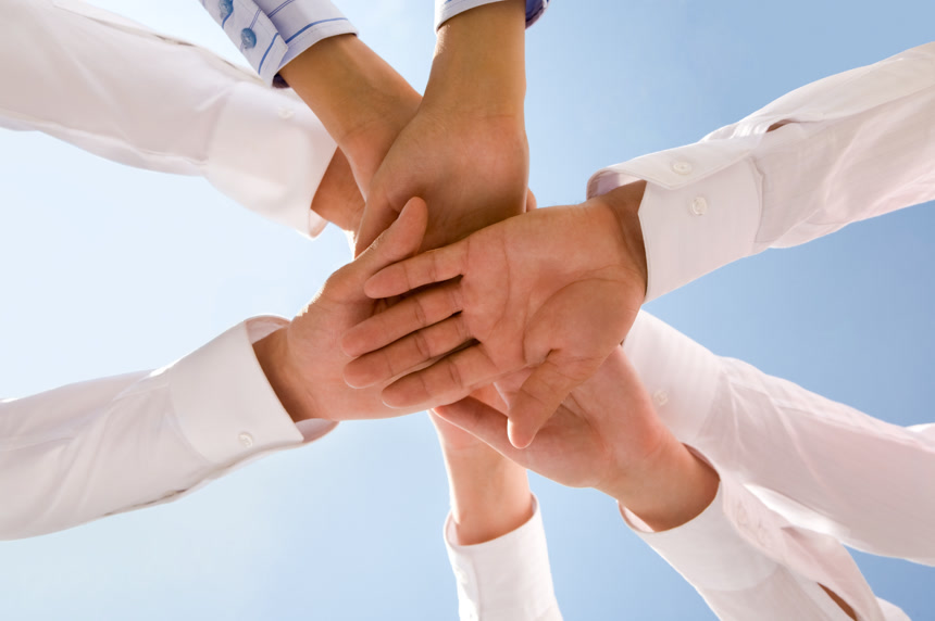 在天空背景中一群人把手叠在一起