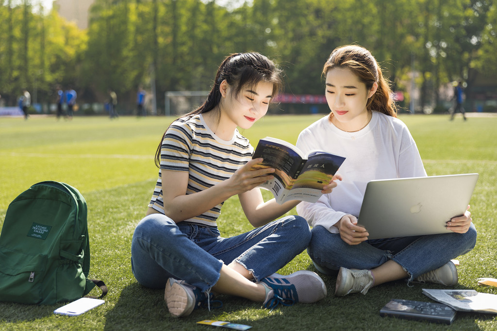 学生朋友在草坪上交流读书图片