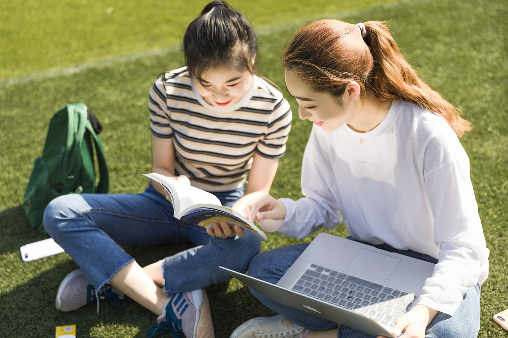 学生朋友在草坪上交流图片