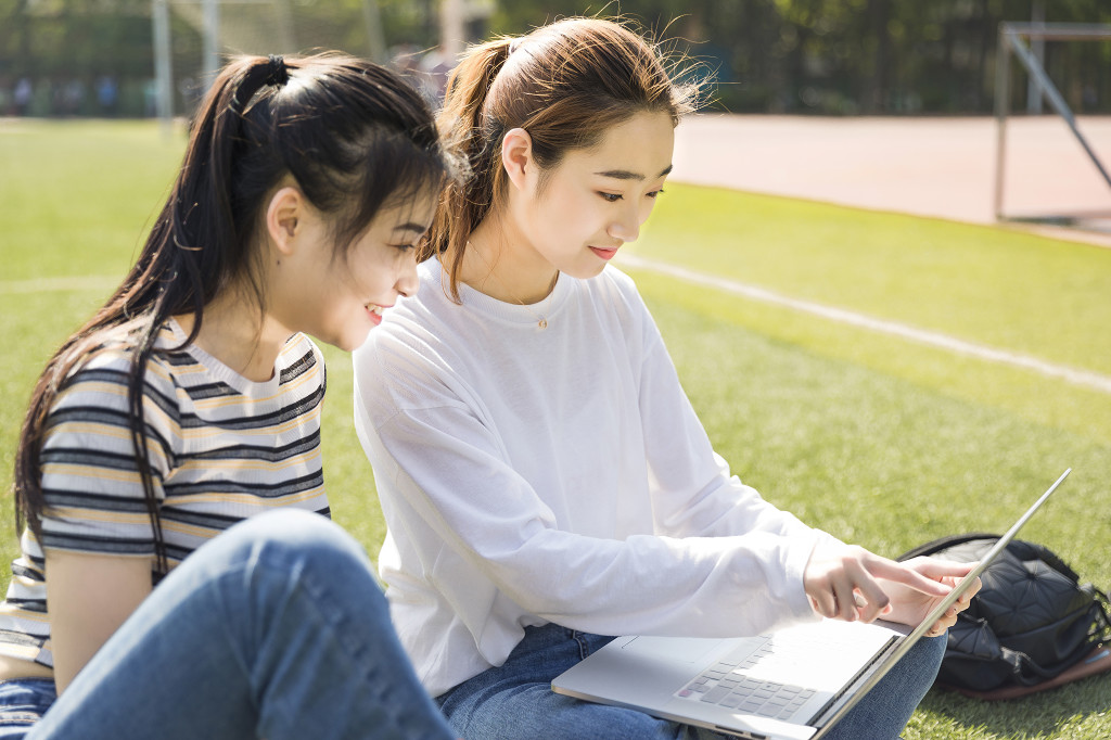 学生朋友在草坪上交流读书图片