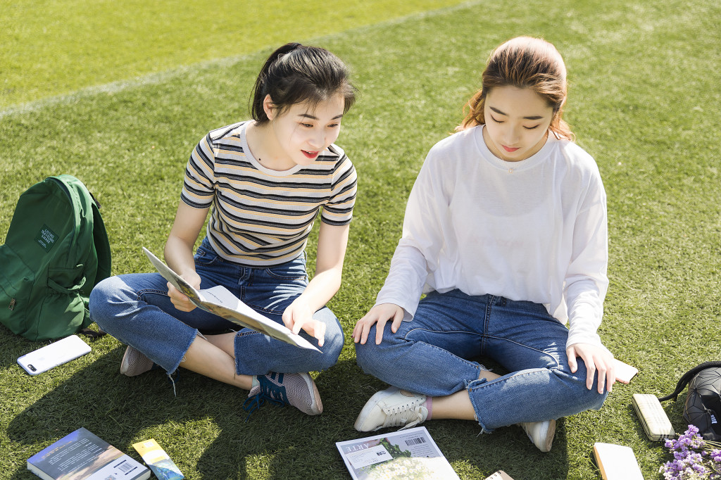 学生朋友在草坪上交流读书图片