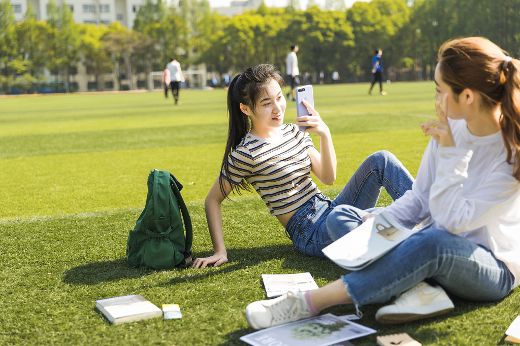 学生朋友在草坪上嬉戏读书图片