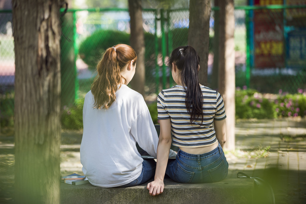 校园小路上朋友闺蜜坐在石板凳上背影图片