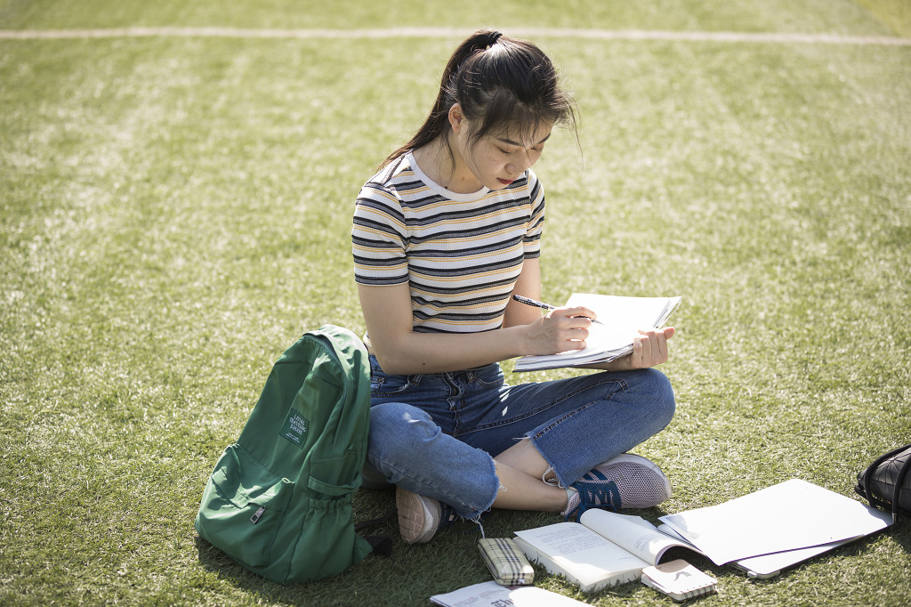 校园美女学生草坪上看书图片