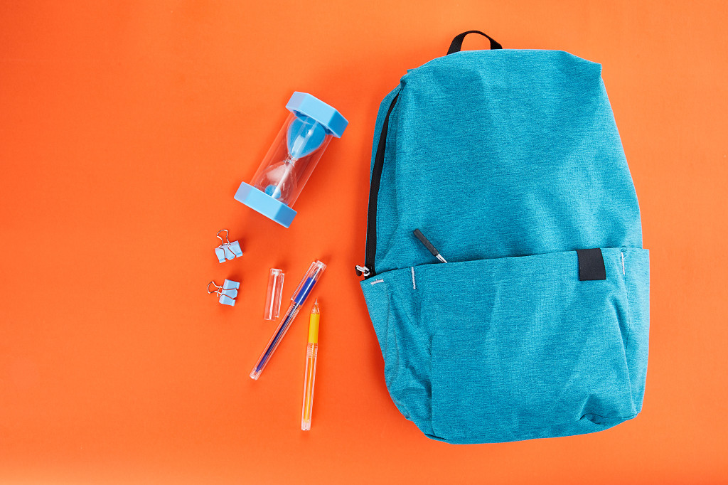 开学季蓝色书包文具在橙色背景上的场景配图俯视图