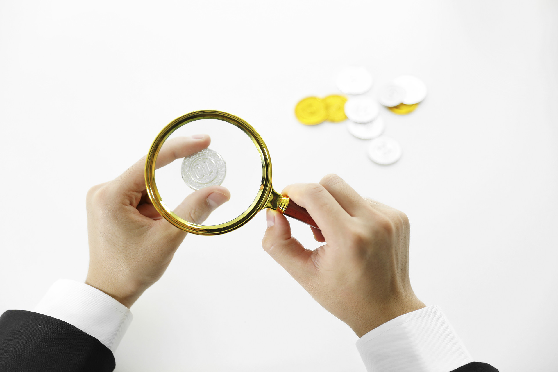 灰底商务手拿放大镜金币银币理财投资金融