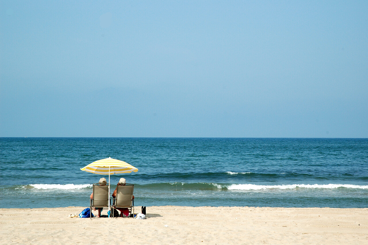 自然风景旅游度假海岸线沙滩太阳伞下的两个人人物图片