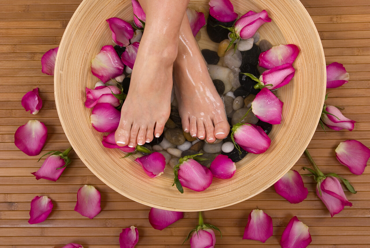 足部特写中医足浴足疗养生石头按摩粉色玫瑰花瓣水里的一双脚足疗按摩脚部