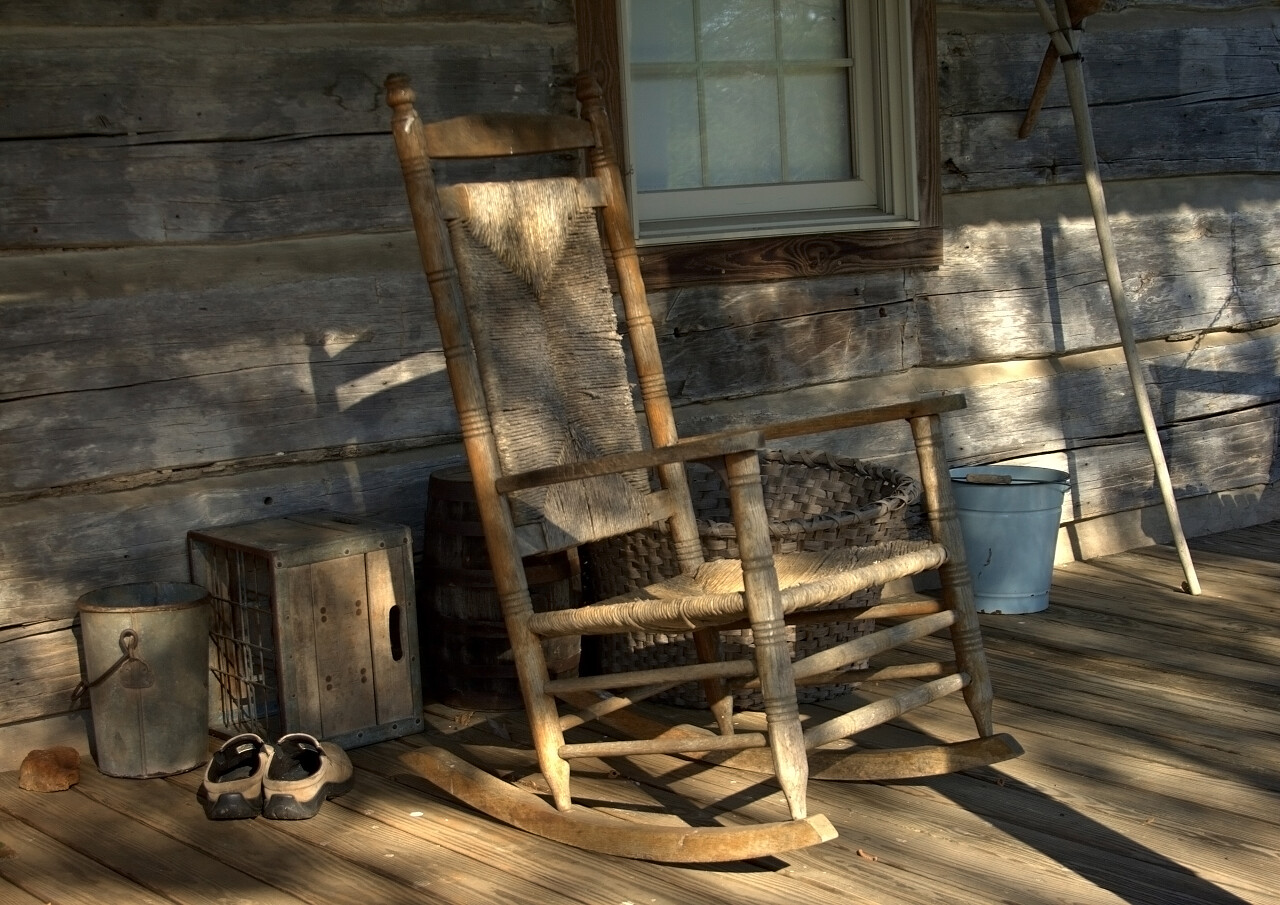 自然风景阳光照耀下木屋走廊上的老摇椅