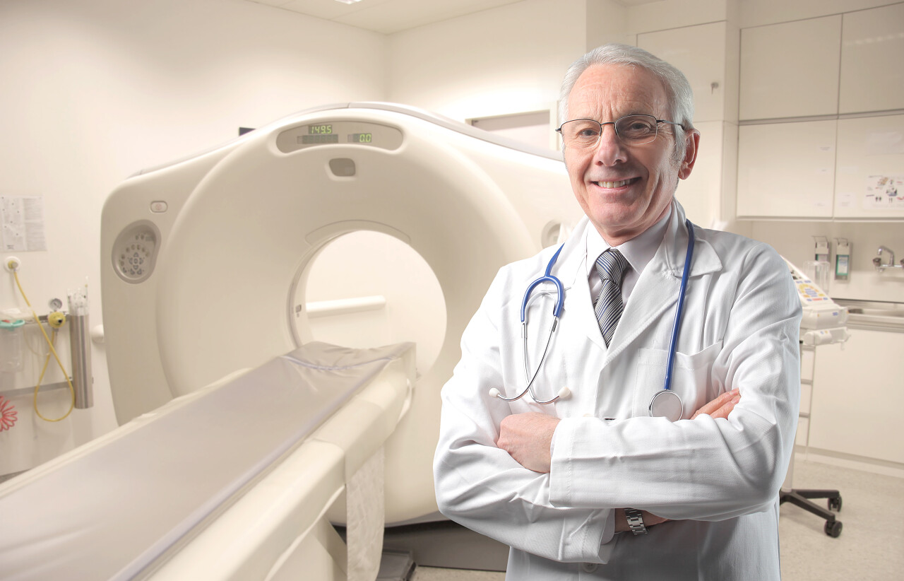 站在磁共振扫描设备边微笑的年纪大的外国医生人物图片