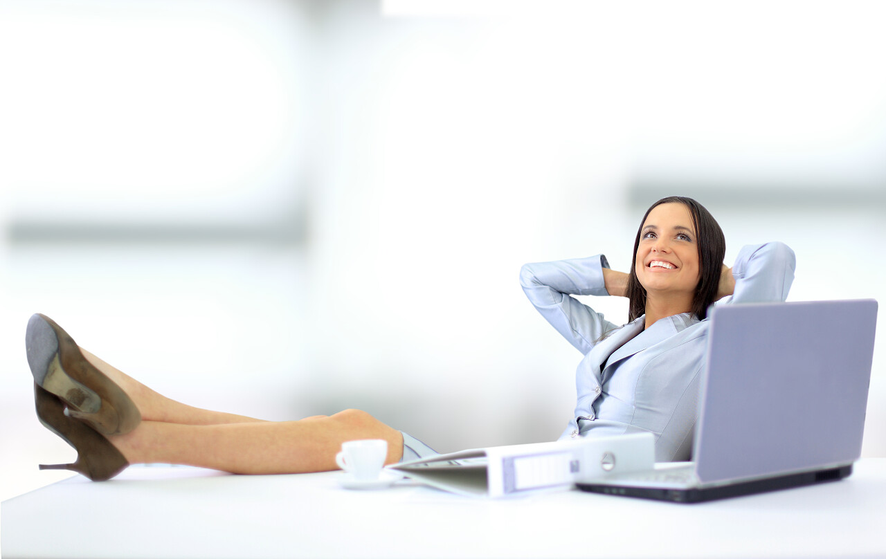 商务女性背靠座椅脚放桌子微笑休息