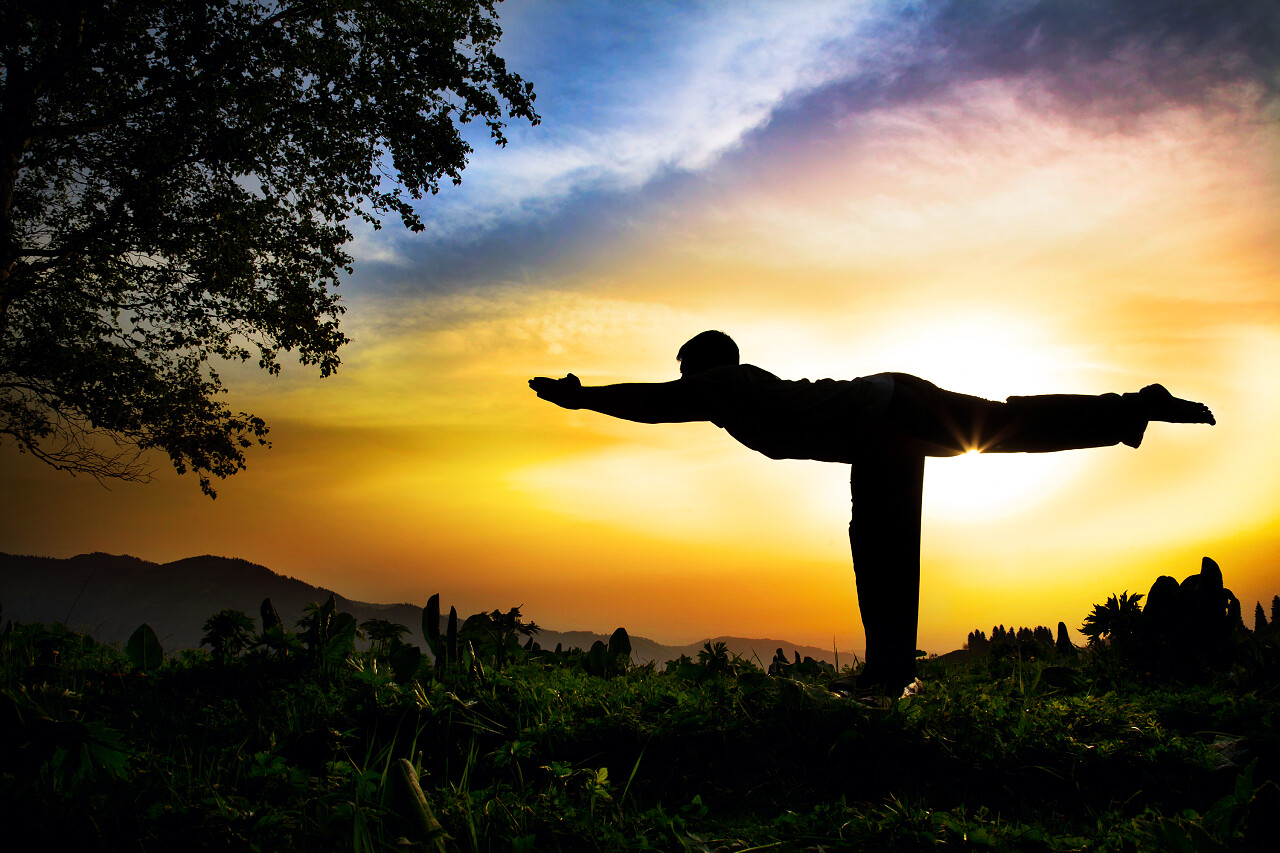 夕阳下独立身体和手向前的瑜伽人物剪影户外瑜伽户外瑜伽