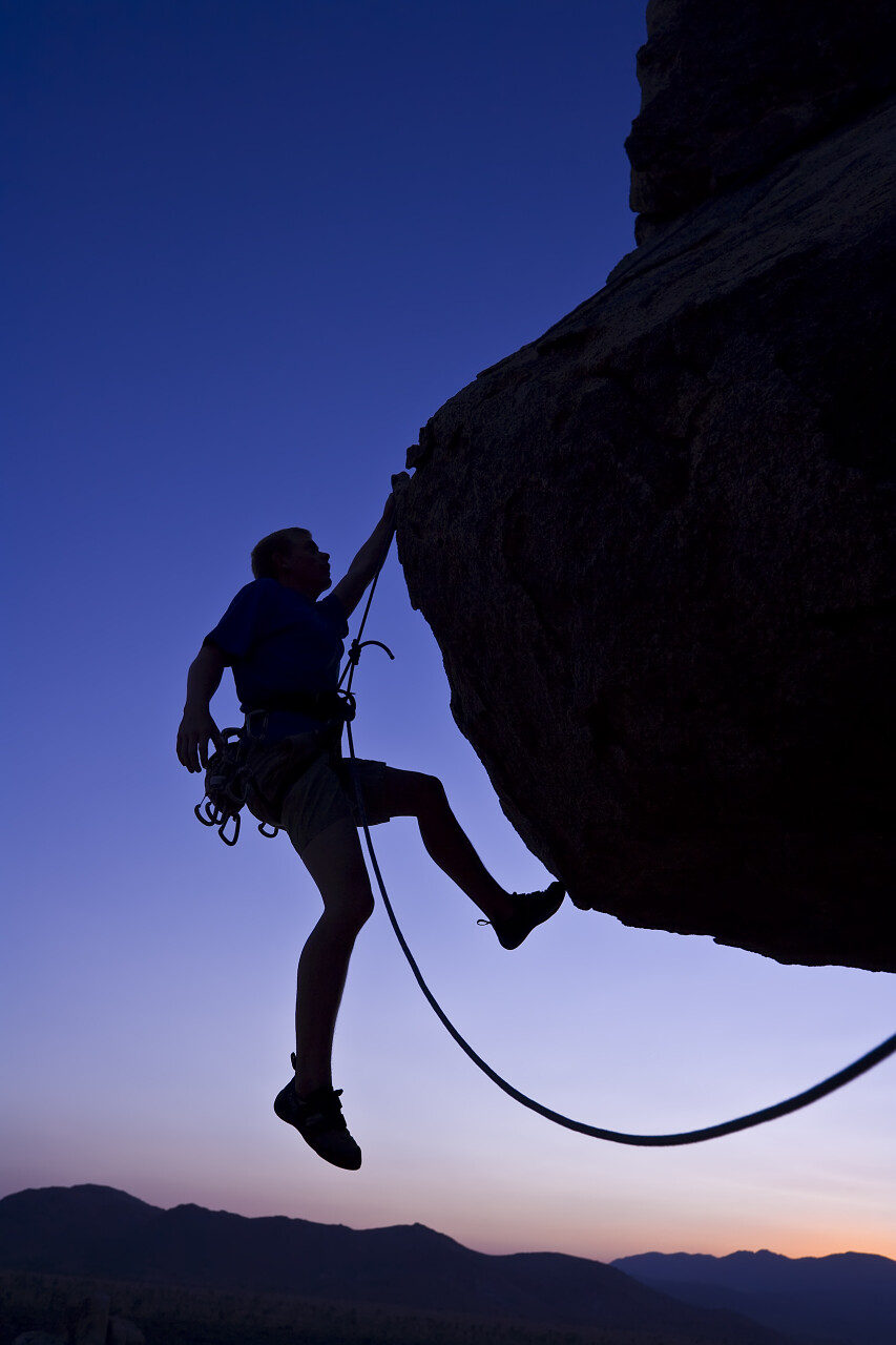 夕阳下的莫哈韦沙漠有一位正在攀登的登山者奋斗精神努力努力坚持不懈