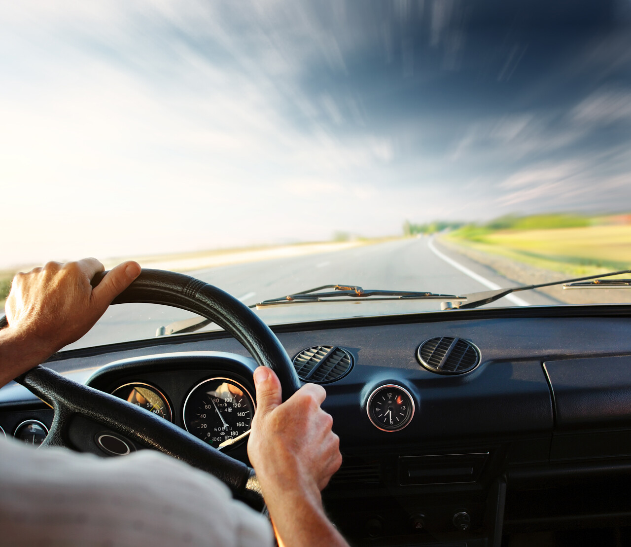 双手放在方向盘的一辆汽车和蓝蓝的天空模糊云