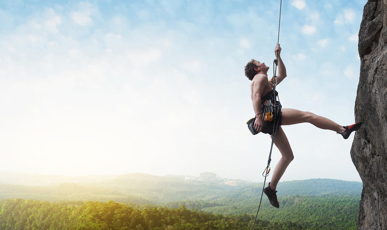 悬崖上挂的年轻男性登山者奋斗精神努力努力坚持不懈