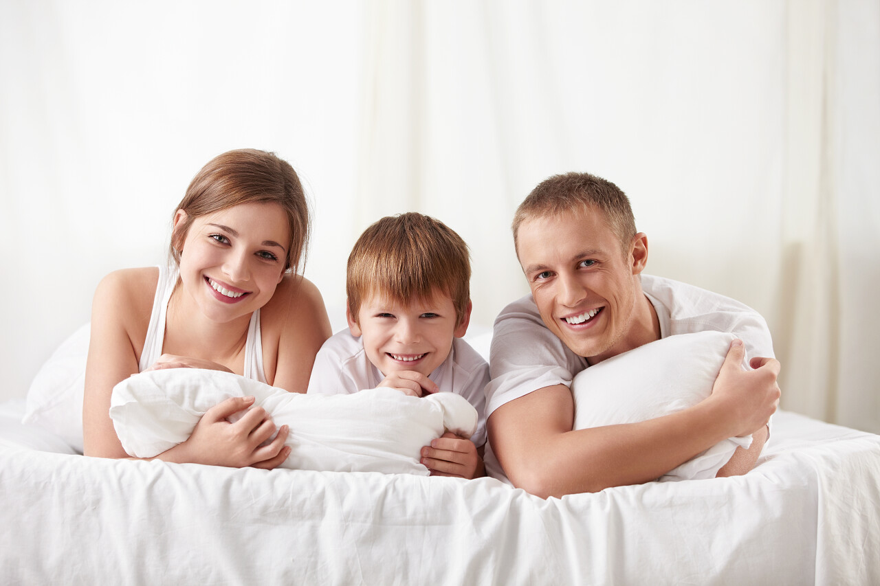 微笑中一间卧室在家里的家庭幸福一家三口