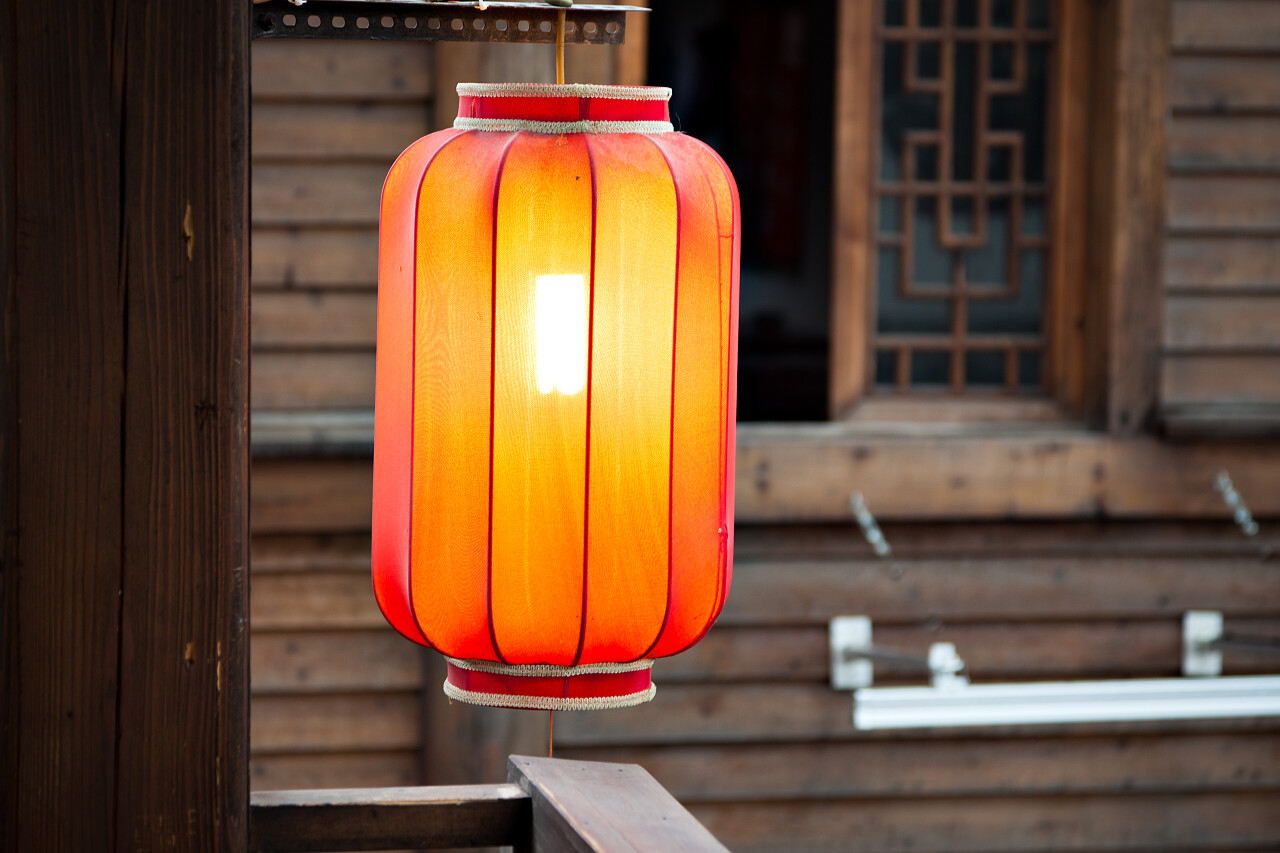 由传统的木墙背景悬挂红灯笼柱上