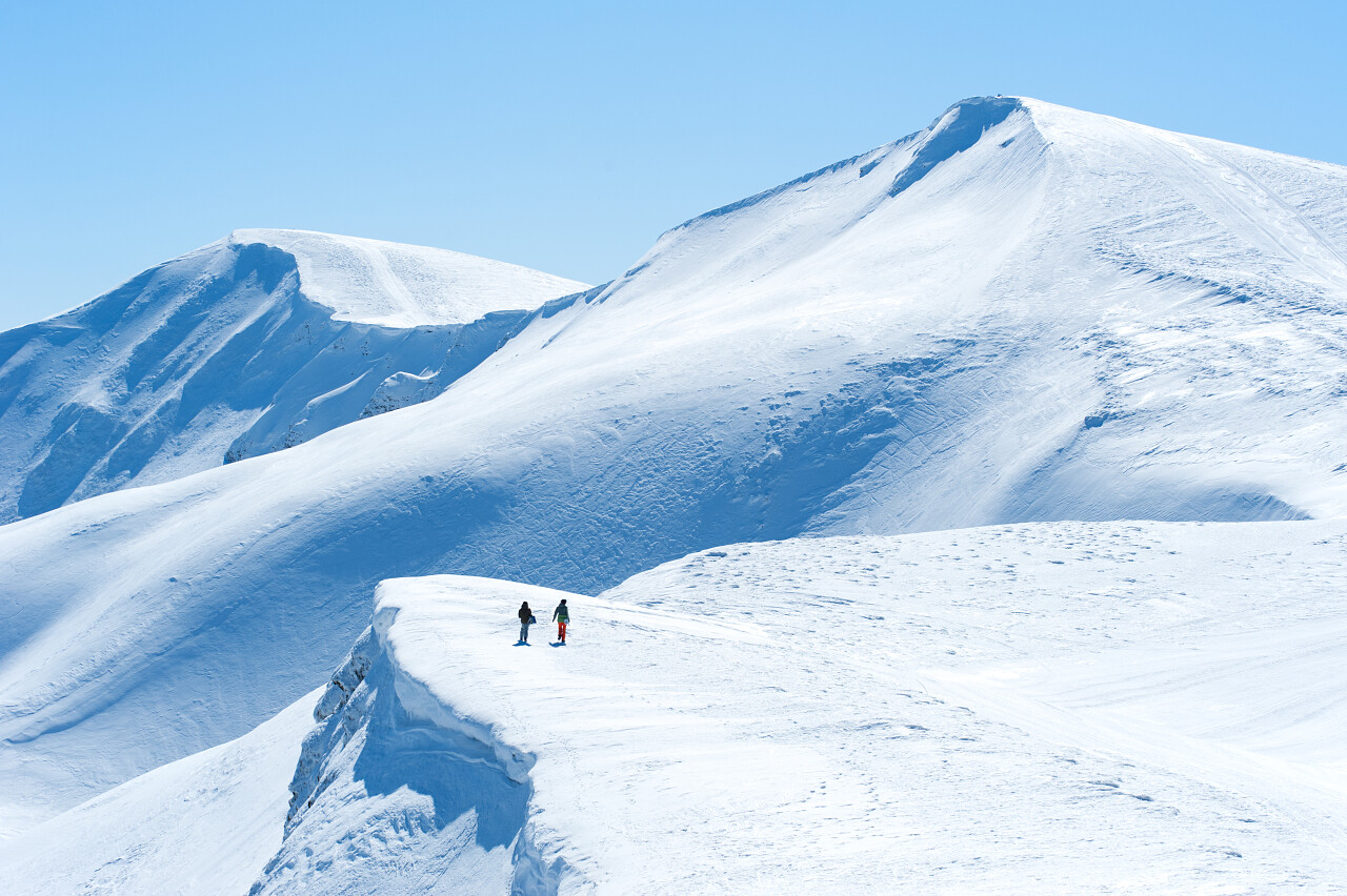 山和雪山两个滑雪板或滑雪者在远处的风景