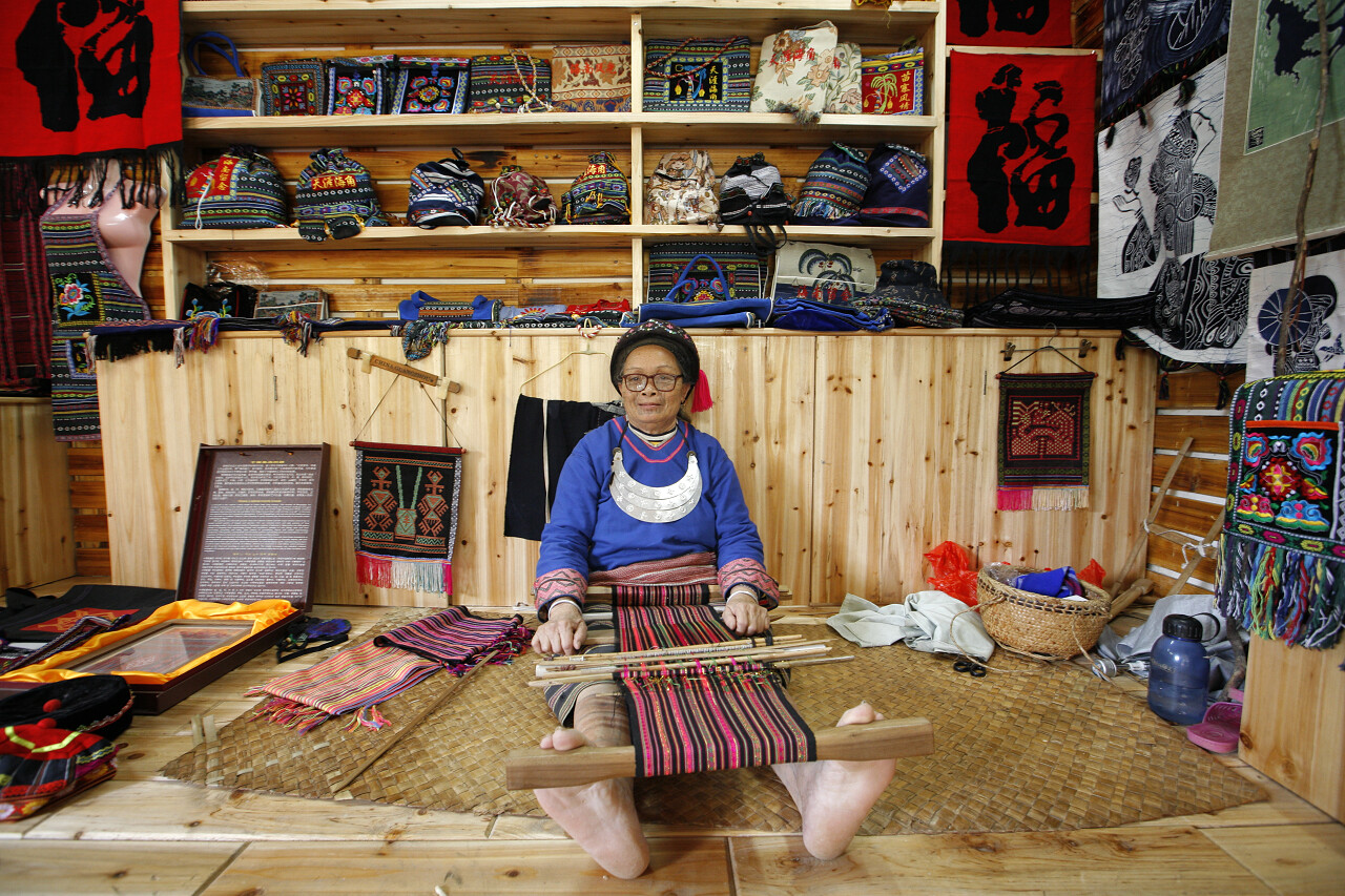 老织工做地毯黎族苗族在货架上摆满产品的背景下