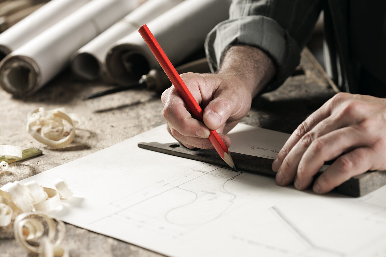 使用红铅笔在蓝图上画图纸的木匠