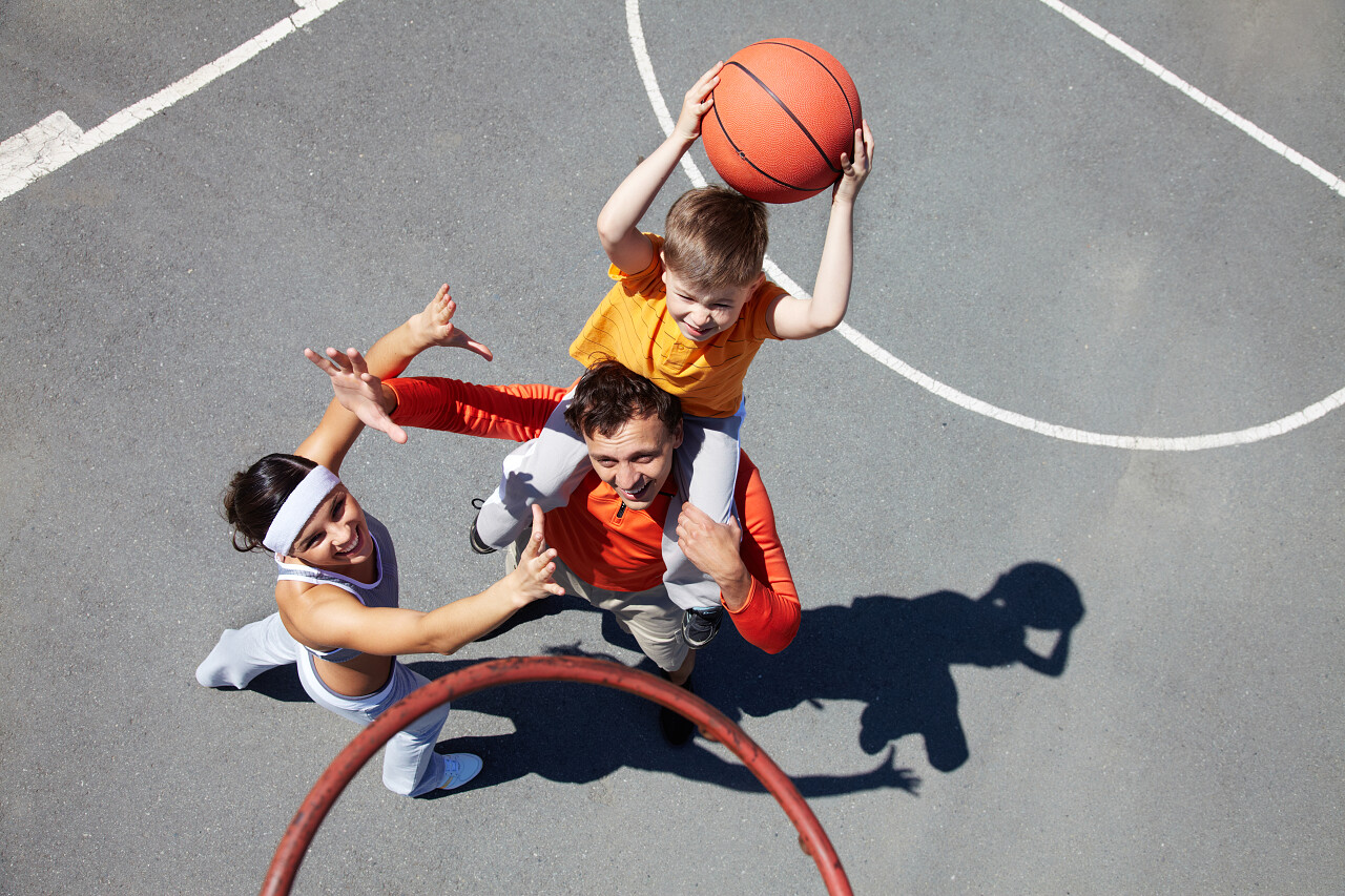 父母带小儿子户外篮球场打篮球互动