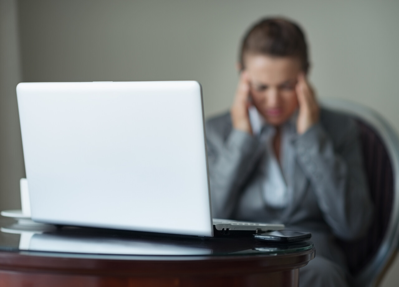 商业女性头痛背景中强调的办公桌上电话和便携式计算机特写压力疲劳辛苦工作焦虑疲劳烦躁犯困困扰