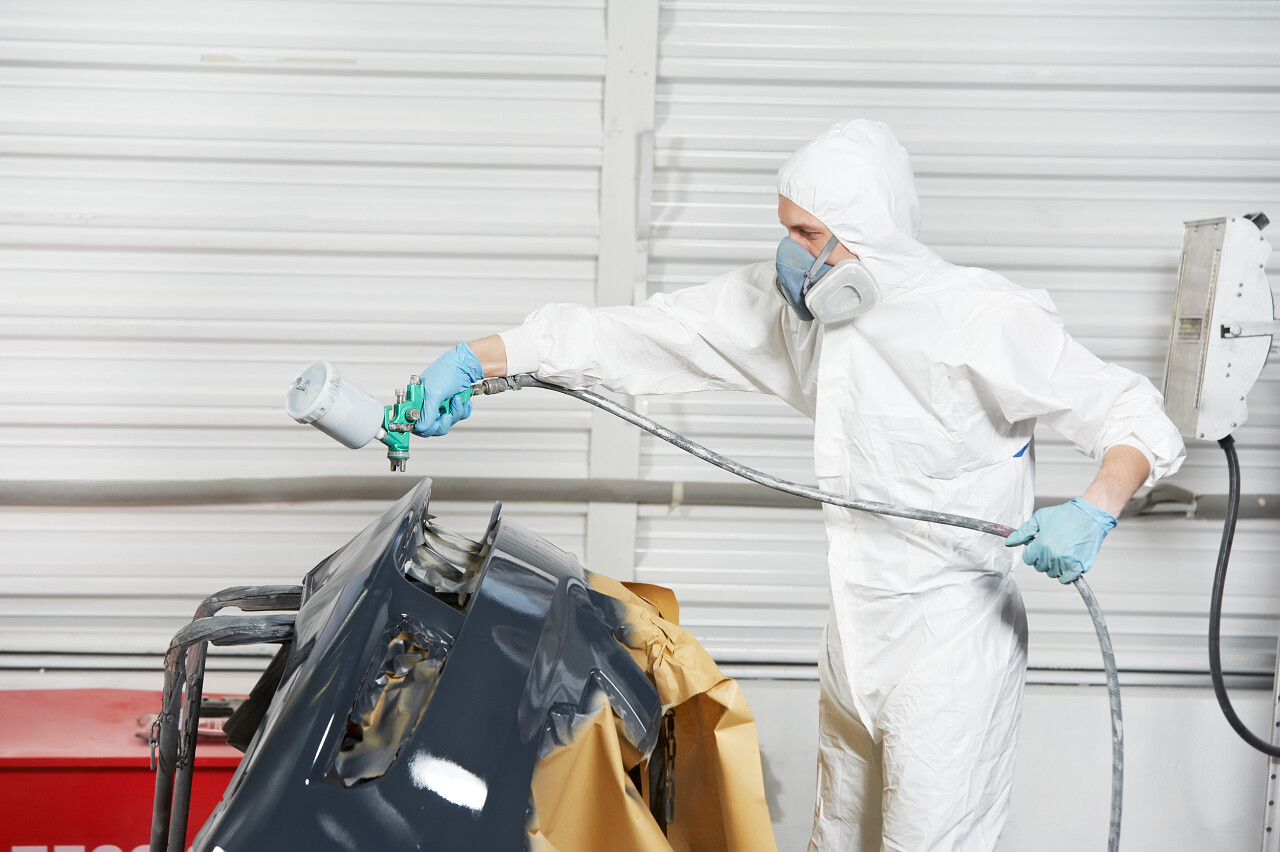 自动机械工人画车在汽车保险杠修复并通过喷雾的黑颜色漆续订服务车站店