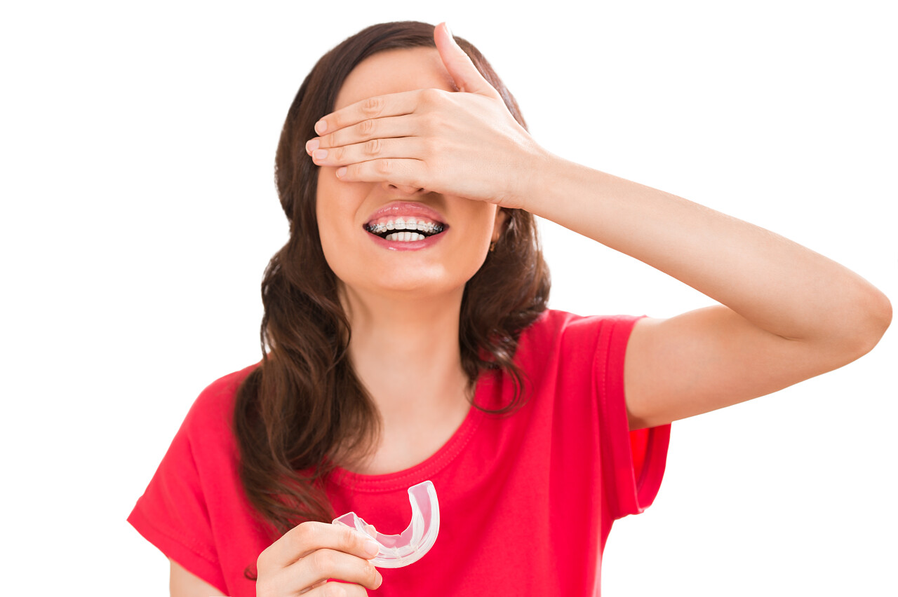 魅力女人牙套正畸控股硅橡胶教练和关闭眼睛特写肖像舒适隐形正畸治疗概念牙齿矫正修复笑容笑脸