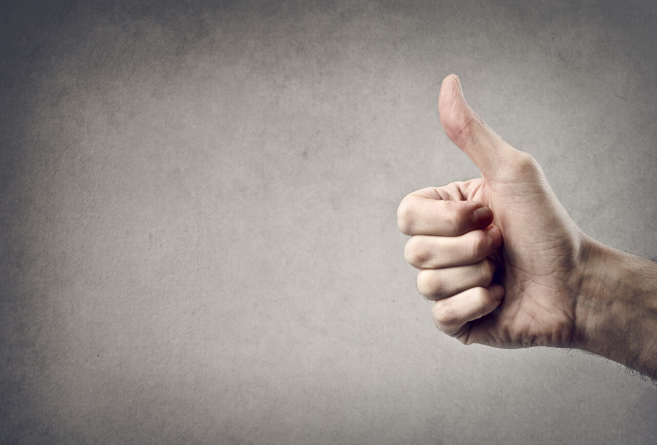 在灰色背景上用大拇指向上的手加油点赞点赞手势