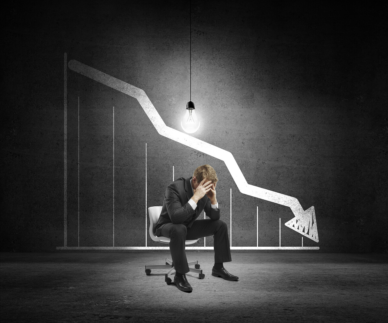 悲伤的商人坐在椅子上和墙上绘制图表