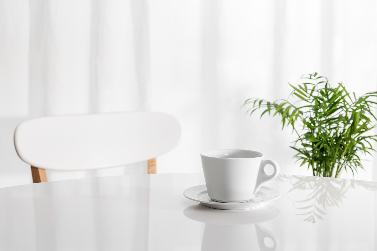 在厨房桌子上用绿色的植物在背景中的白色杯子